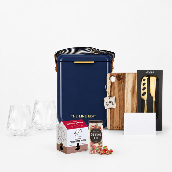 The Festive Edit Gift Set - A navy gift set featuring glasses, a wooden board, a knife, canned drinks, and festive treats. Includes a branded bag.