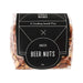 The Knock Off for Christmas Pack - A clear plastic bag containing roasted beer nuts, showcasing a mix of light brown and tan nuts. The bag features a black label with branding.