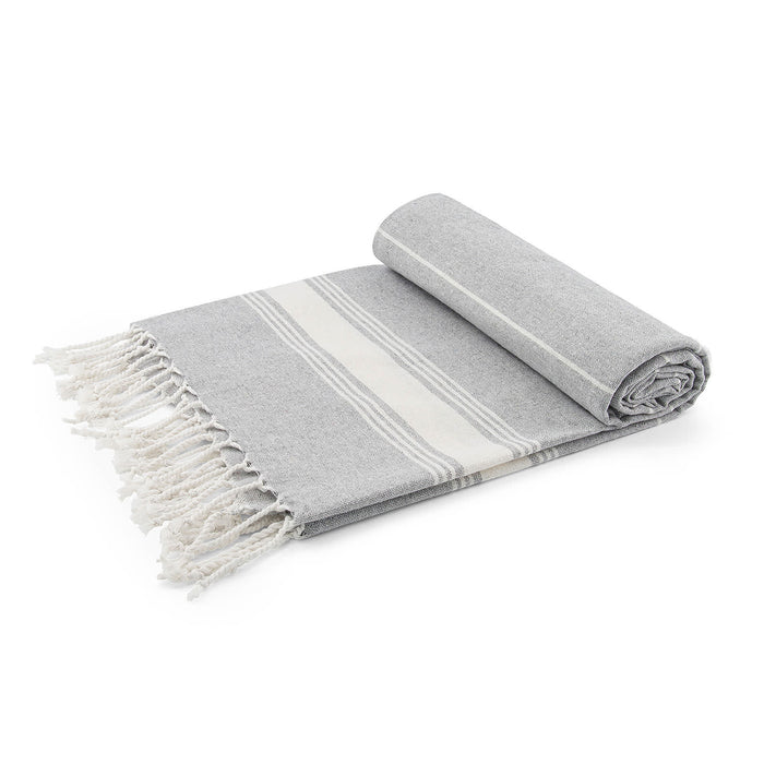 The Coastal Edit - A rolled grey blanket with white stripes and fringed edges, featuring a soft, textured fabric.