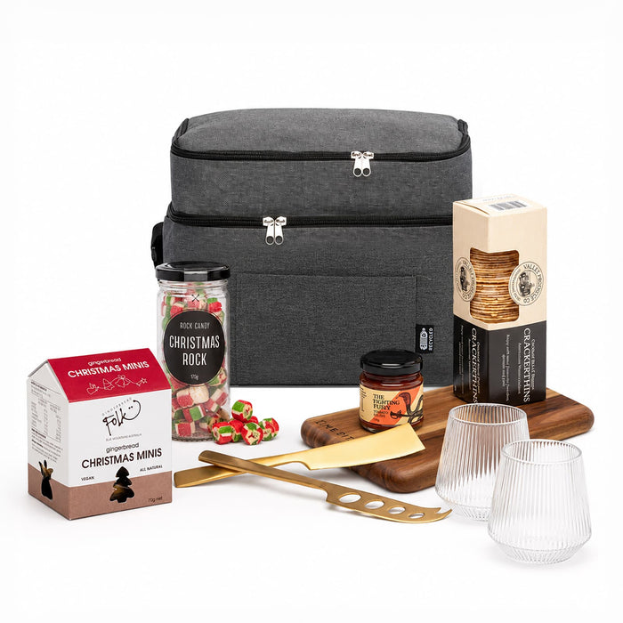 The Refined Graze: Christmas Edition - A grey insulated bag filled with gourmet snacks, including biscuits, sweets, and a wooden cheese board with utensils.