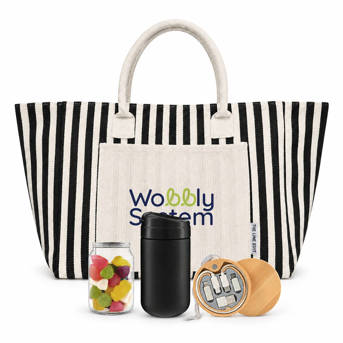 The Good Stuff Pack - A striped tote bag in black and white with a cream pocket, a jar of colourful sweets, a black drink container, and a wooden item.