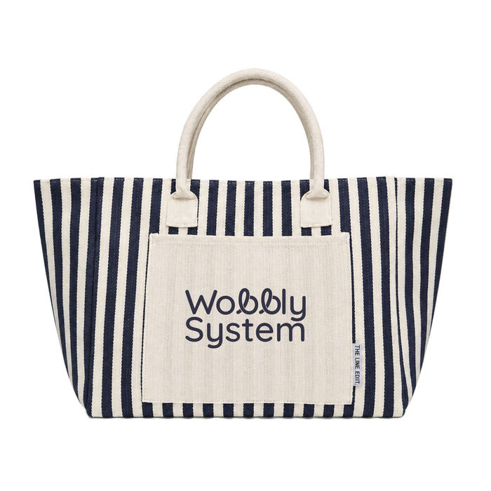 The Good Stuff Pack - A large striped tote bag in navy and cream, featuring a front pocket with a logo.