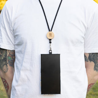 Shadow Phone Neck Lanyard - A phone neck lanyard featuring a wooden clip and a black strap, securely holding a smartphone.