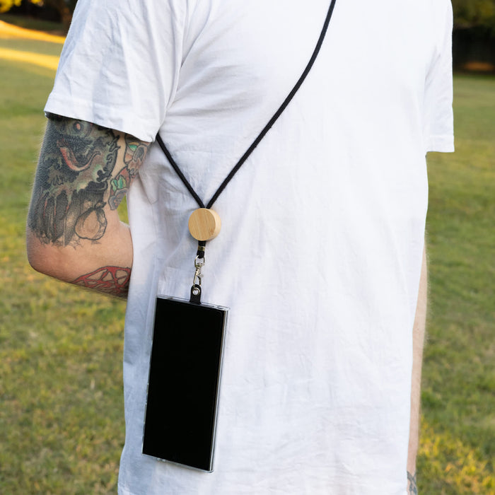 Shadow Phone Neck Lanyard - A phone lanyard featuring a black strap and wooden bead, securely holding a smartphone on a person's back.