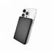 Axial by Nomis Solid State Power Bank - A black solid-state power bank is positioned against a silver smartphone, highlighting its sleek design and portable size.