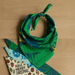 Very Kool Cooling Bandana - A green bandana featuring a tropical leaf design, tied in a knot on a wooden surface.