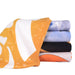 Bath Towel - A stack of face washers in various colours including orange, blue, and black, featuring vibrant patterns.