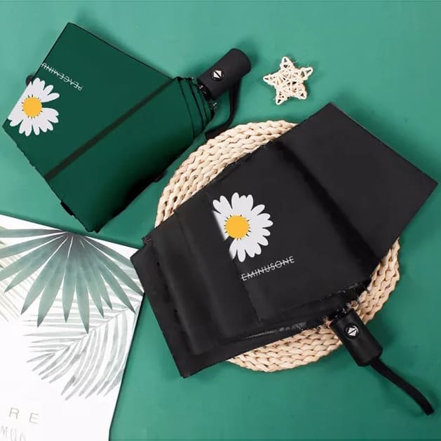 Full Colour Poppins Umbrella - A green and black umbrella with a daisy design, featuring a logo and displayed on a round woven mat.
