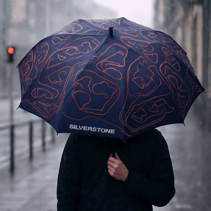 Full Colour Corporate Umbrella - A full-colour navy umbrella with an abstract design and logo, held by a person in a rainy urban setting.