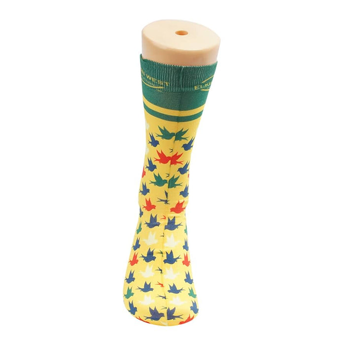 Magic Dress Socks - Bright yellow socks featuring a multicoloured leaf pattern, displayed on a sock model. Contains a logo.