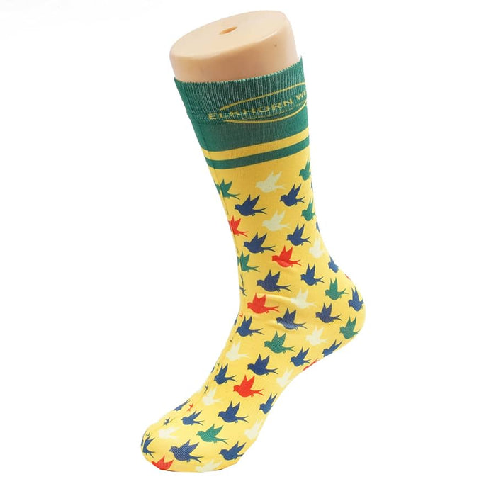 Magic Dress Socks - A brightly coloured yellow sock featuring a pattern of green, red, and blue leaves, with a green cuff at the top.