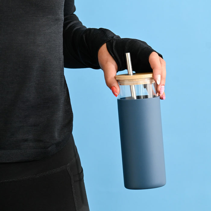 Sunrise Smoothie 500mL Tumbler - A drink bottle with a blue exterior, clear top, and bamboo lid, featuring a straw and held by a person.