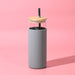 Sunrise Smoothie 500mL Tumbler - A drink bottle with a grey silicone sleeve, clear glass body, and wooden lid, featuring a reusable straw.