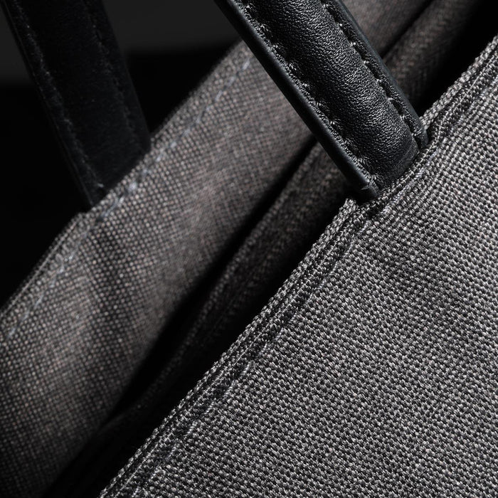 Swissdigital Arosa Tote Bag - A grey tote bag featuring dark green leather handles and stitching, with a close-up view of the fabric texture.