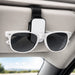 Car Visor Sunglass Holder - A black and white car visor sunglass holder with sunglasses attached, mounted on a car's visor.