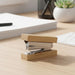 Bamboo Stapler - A bamboo stapler with silver metal components, placed on a wooden desk, alongside a plant and stationery items.