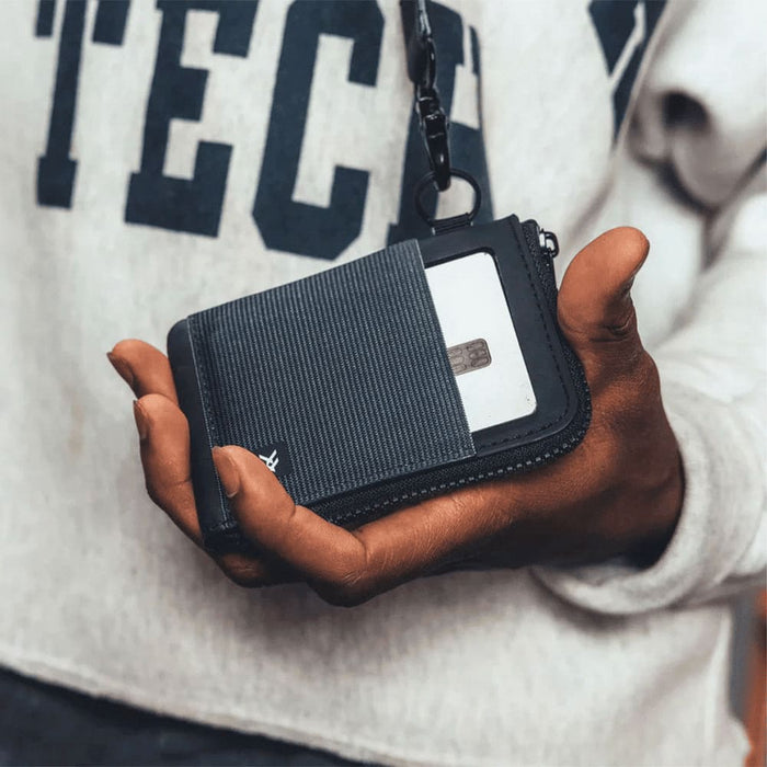 Thread Zipper Wallet - A hand holding a black and grey Thread Zipper Wallet, featuring a zippered compartment and a card slot.