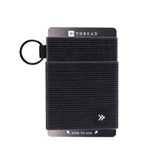 Thread Elastic Wallet - A black Thread Elastic Wallet features a textured design and includes a keyring attachment. It has a branding logo.
