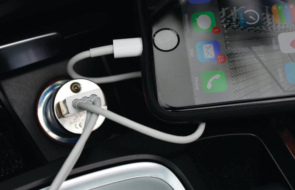 Spirit Techno Kit - A phone charging cable connected to a silver car charger, with a smartphone displaying apps and notifications.