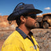 Trekk Recycled Surf Hat - A blue recycled surf hat worn by a man in safety gear, with sunglasses, set against an industrial background.