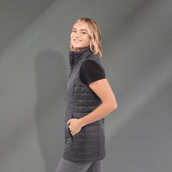 Women's Telluride Lightweight Packable Insulated Puffer Vest - A fitted women's puffer vest in dark grey with a high collar and side pockets. It has a logo on the chest.