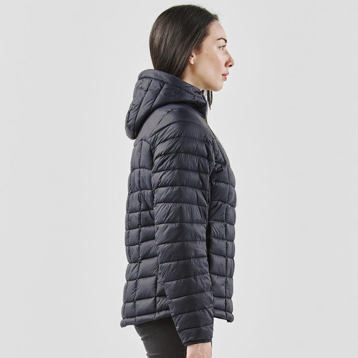 Women's Tundra Thermal Jacket - A woman's puffer jacket in dark navy, featuring a hood and a quilted design, with a logo on the sleeve.