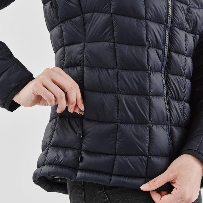 Women's Tundra Thermal Jacket - A women's puffer jacket in navy blue, featuring a quilted design and side zipper pockets. Includes branding.