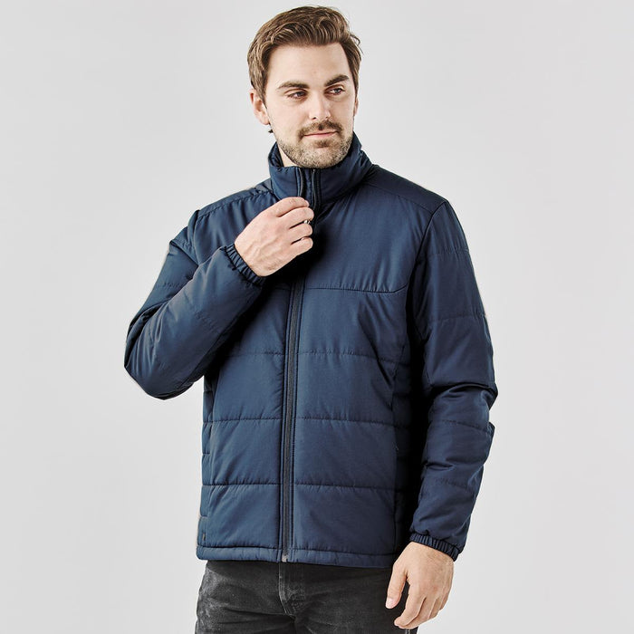 Men's Sierra Thermal Jacket - A male model wearing a navy blue puffer jacket with a high collar and zip closure. The jacket has an elasticised hem.