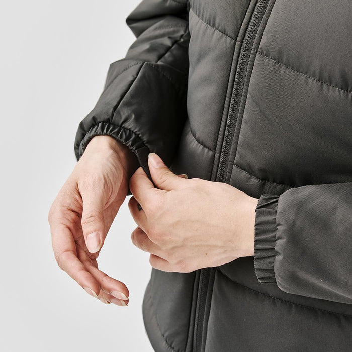 Women's Sierra Thermal Jacket - A close-up of a woman's hands adjusting the cuff of a women's grey puffer jacket. The jacket has a logo.
