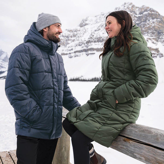 Men's Elkridge Parka - A man in a navy puffer jacket and a woman in a green puffer coat stand together outdoors in a snowy landscape.